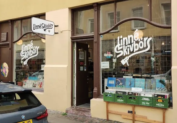 Linné Skivbörs fasad på Andra Långgatan 20 — handmålad logotyp i skyltfönstren, öppen dörr och skivbackar ute på trottoaren
