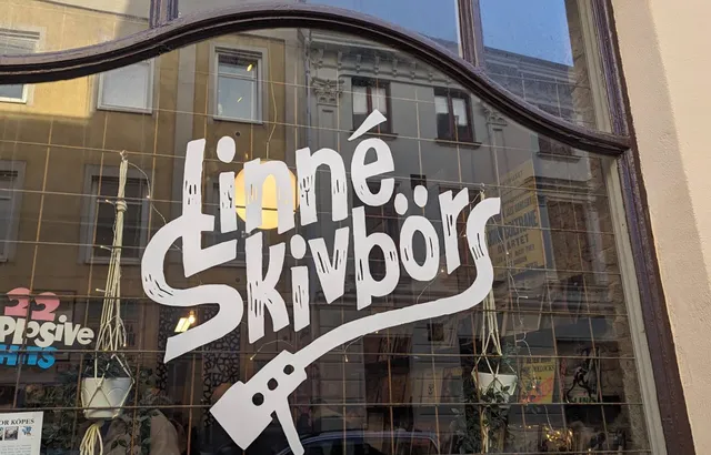 Linné Skivbörs handmålade logotyp i skyltfönstret, med en Coltrane-affisch och varmt ljus innanför rutan